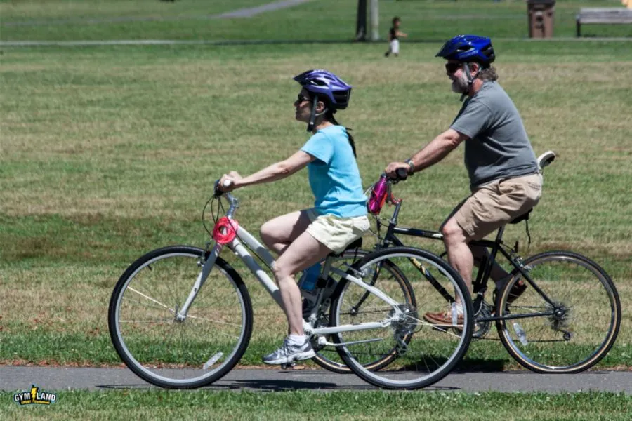 2 مرد و زن در یک پارک دوچرخه‌سواری می‌کنند.