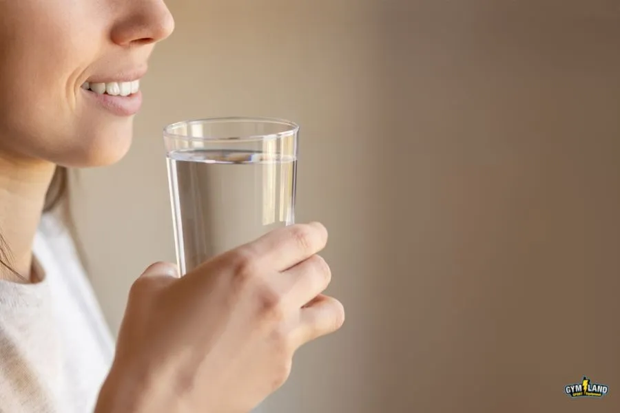 زنی در حال نوشیدن آب. تمرکز عکس بر روی لیوان آب است.